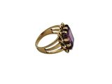 a close up of a gold ring with a purple stone