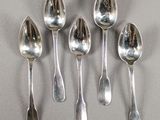 six cuillères en argent sont alignées sur une table