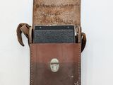 a cell phone in a leather case on a white surface