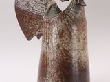 a brown vase with an angel on it on a white background