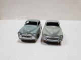 two toy cars sitting side by side on a white surface