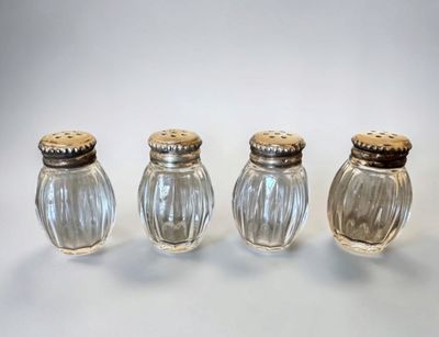 three glass salt and pepper shakers sitting on top of a table