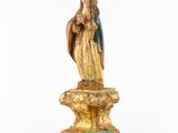a statue of the virgin of guadalupe on a pedestal with a green box