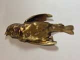 a gold bird that is sitting on a white table