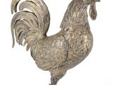 une statue en argent représentant un coq sur fond blanc
