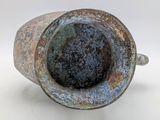 a large metal vase with a brown patt on it