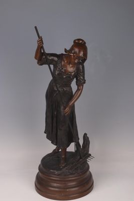 bronze statue of a woman holding a gun and a bird