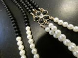 two strands of black and white pearls with a gold clasp