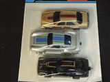 three toy cars in a package on a black surface