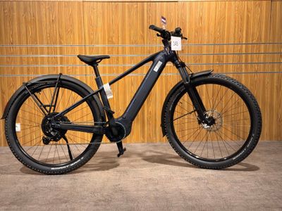 une photo d'un vélo électrique noir garé devant un mur en bois