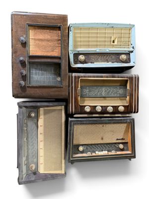 plusieurs radios à l'ancienne empilées les unes sur les autres sur une surface blanche