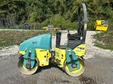 a yellow and blue road roller sitting on top of a gravel road