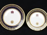 two plates with gold and blue designs on them on a black surface