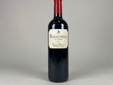 a bottle of red wine sitting on top of a white table