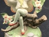 a figurine of a little girl sitting on a tree branch