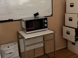 an image of a room with a white board on the wall and a microwave on the table