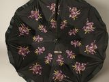 un parapluie noir orné de fleurs violettes, accroché au mur
