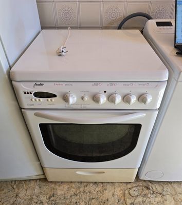un ordinateur portable posé sur une cuisinière, à côté d'une machine à laver