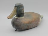 un gros plan d'un canard en bois posé sur une surface blanche