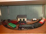 un circuit de train miniature posé sur une table, avec une maison en arrière-plan