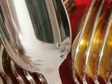 a lot of spoons and forks on a red table cloth