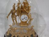 une horloge en or sous un dôme de verre sur fond blanc