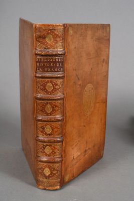 an old book sitting on top of a wooden table next to a vase
