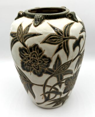 un vase blanc orné de fleurs noires, posé sur un fond blanc