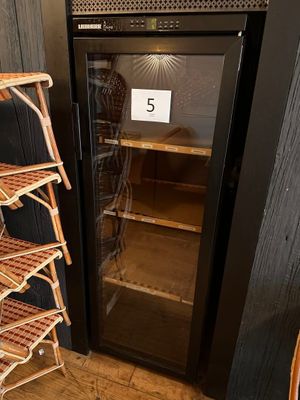 a black refrigerator with a glass door next to a stack of shelves