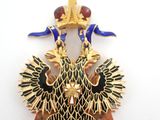 a gold and blue brooch with two birds on it