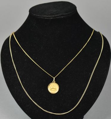 a gold necklace with a coin on a black mannequin