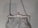 a silver purse with a chain handle hanging from it ' s side