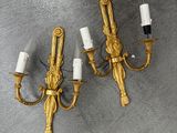 trois appliques dorées avec des bougies blanches posées sur un support gris