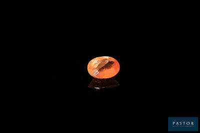 a close up of a small orange stone on a black surface