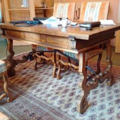a large wooden table with chairs and a rug on the floor