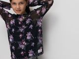 the young girl is posing against a wall with her hands on her head
