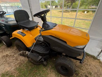 une tondeuse à gazon jaune garée à côté d'une tondeuse à gazon verte