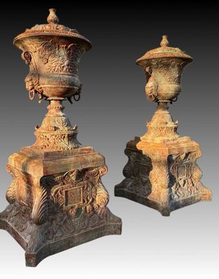 pair of antique cast iron urns on pedestals on a gray background