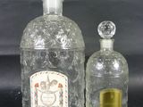 deux bouteilles en verre transparent posées l'une à côté de l'autre sur une surface noire