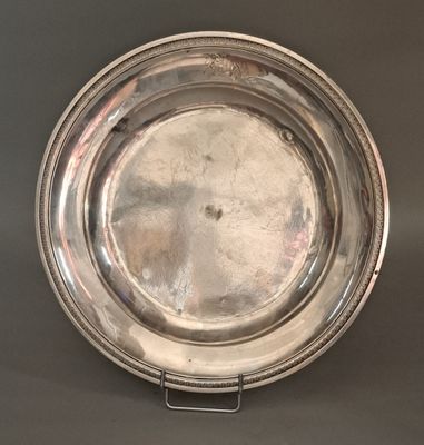an antique silver plate on a stand on a gray background