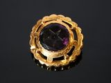 un gros plan d'une bague en or ornée d'une pierre violette au centre