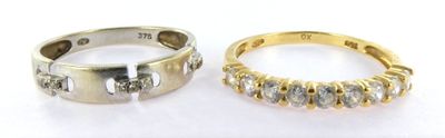 two gold and silver rings with diamonds on them on a white surface
