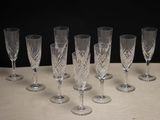 six clear wine glasses lined up on a table with a black background