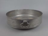 an antique silver plate with a handle on a gray background