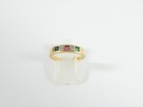 a close up of a yellow gold ring with three different colored stones