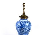 a blue and white vase with a gold lid on a stand