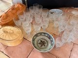 plusieurs verres et un bol posés par terre à côté d'une valise