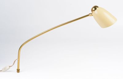 a gold desk lamp with a white shade on a white background