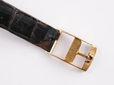 a close up of a watch with a gold buckle on a white surface