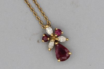 un gros plan sur un collier en or orné d'une croix en pierres rouges et blanches